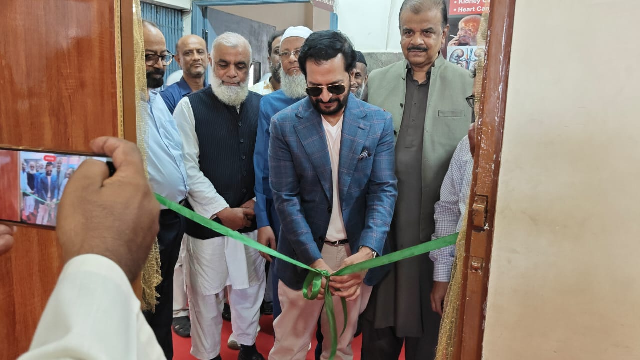 A visiting leader cuts a green ribbon during an institutional visit