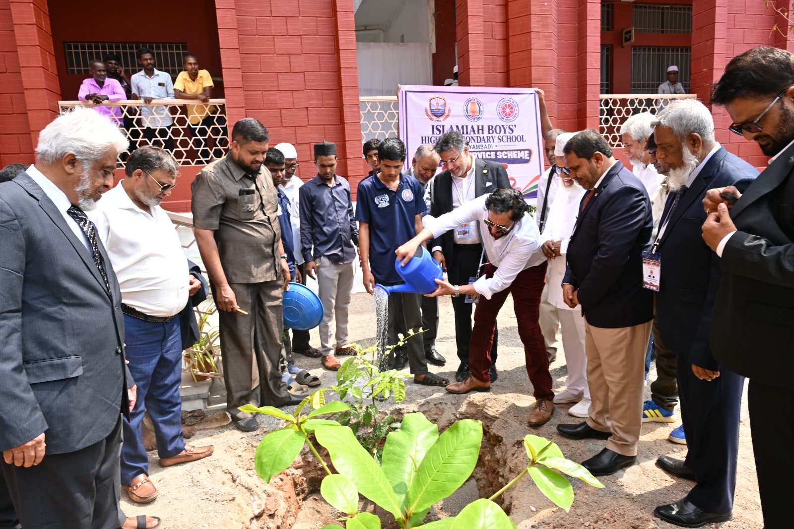 Visitors and students watering a young tree outside Islamiah Boys’ Higher Secondary School